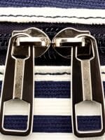 Große Reisetasche für Damen mit Hängefächern, Streifenmuster und Bändern. Details zum Verschluss Große Reisetasche für Damen mit Hängefächern, Streifenmuster und Bändern. Details zum Verschluss